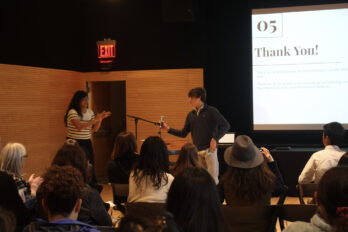 Male speaker holding a microphone in front of an audience